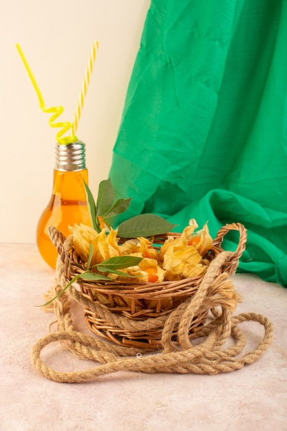 A front view orange peeled physalises inside basket with cocktail on the pink desk  