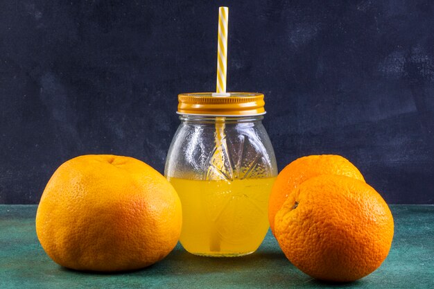 Front view oranges with orange juice in a jar with a yellow straw