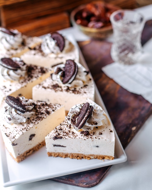 Front view oreo cheesecakes tasty yummy inside white plate on the brown floor