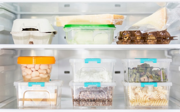 Front view of organized plastic food containers in fridge