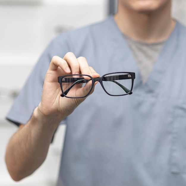 Free photo front view of pair of glasses held by defocused man