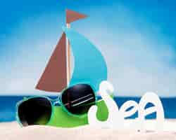 Free photo front view of paper boat on beach with sunglasses