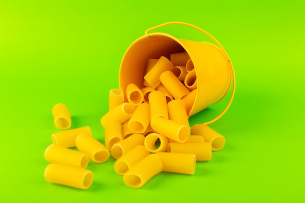 A front view pasta inside basket formed raw inside yellow basket on the green background meal food italian spaghetti