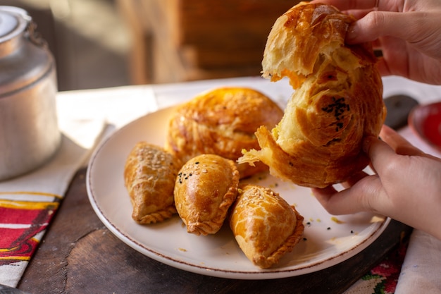 Free photo a front view pastries woman tearing qogal along with other bakeries cookies tea time tasty pastry dough ceremony on the table