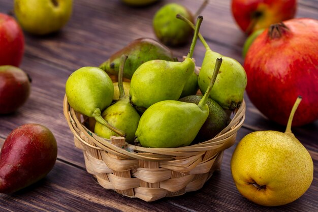 Front view of peaches in basket with other ones and apples pomegranate on wooden surface