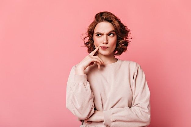 Free photo front view of pensive pretty woman. curly girl thinking on pink background.