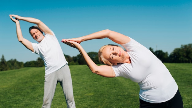 Free photo front view people stretching outdoors