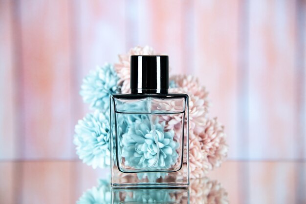 Front view of perfume bottle in front of flowers on beige blurred