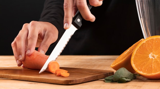 Front view person cutting carrot near orange