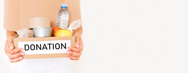 Free photo front view of person holding box of food donation