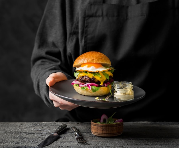 Front view person holding plate with burger