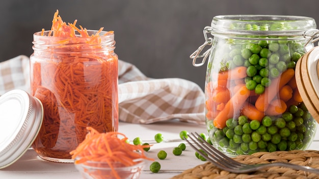 Free photo front view of pickled peas and baby carrots in clear jars