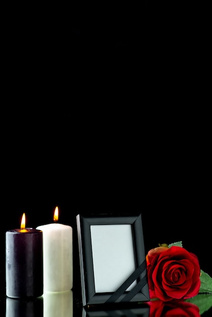 Front view of picture frame with candle and red rose on black