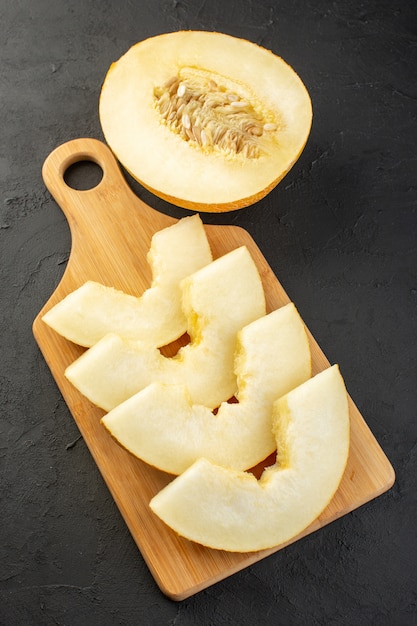 A front view pieced fresh melon mellow juicy and sweet lined on wooden desk and dark