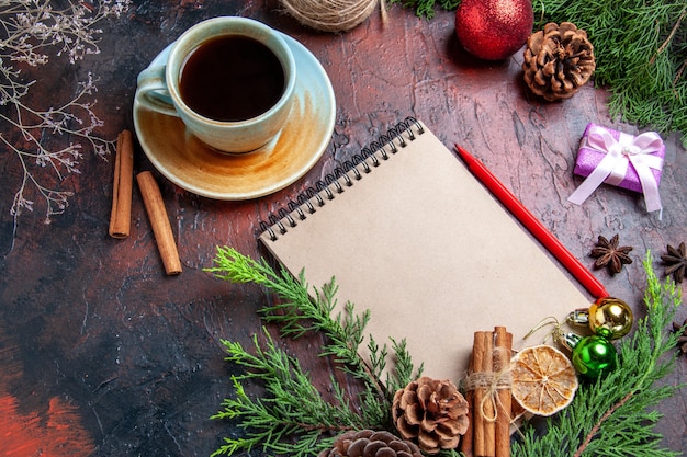 Free photo front view pine tree branches and pinecones on a notebook red pen dried lemon slices straw thread on dark red background