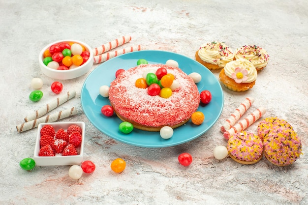 Front view pink cake with colorful candies on white background goodie rainbow candy dessert color cake