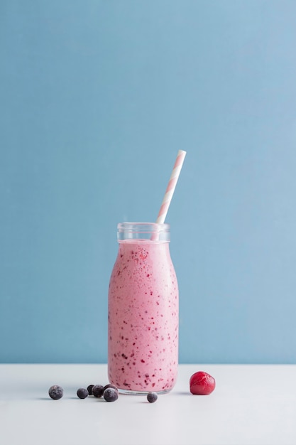 Front view pink smoothie bottle with straw and copy-space