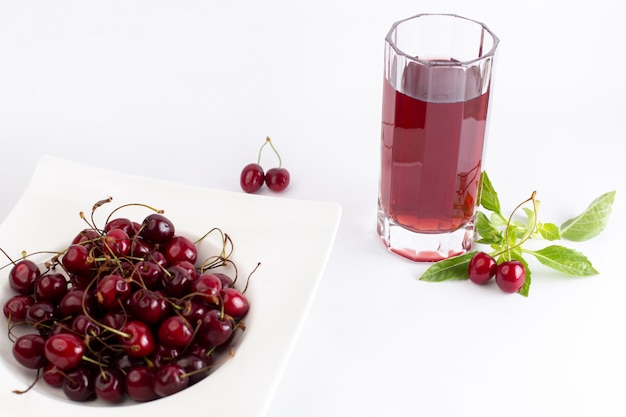 Free photo front view plate with cherries sour and mellow along with cherry juice leaves on white