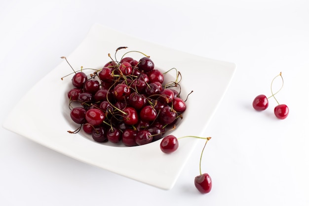 Free photo front view plate with cherries sour and mellow on white