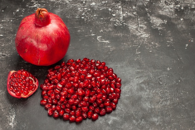 Free photo front view pomegranate pomegranate seeds on dark table free space