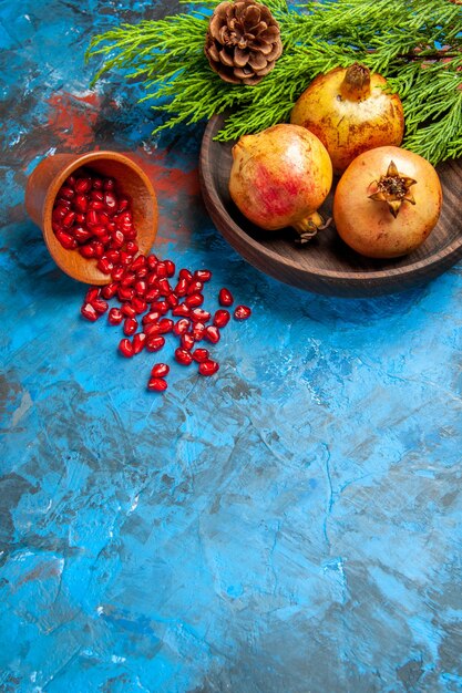 Free Photo front view pomegranate seeds placed in wooden cup with scattered seeds pomegranates on wooden