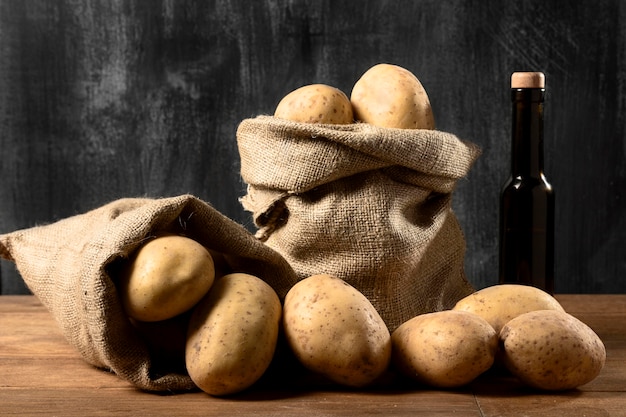 Free photo front view of potatoes in burlap sack with bottle of oil