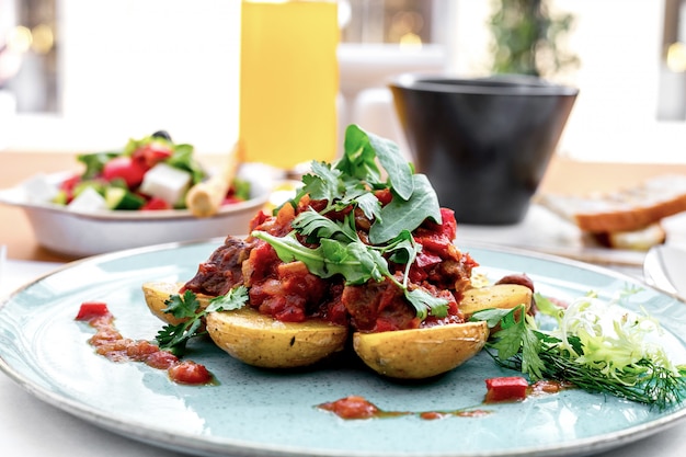 Free Photo front view potatoes with meat in tomato sauce with arugula and greek salad on the table