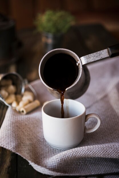 Front view pouring coffee from a kettle into a cup