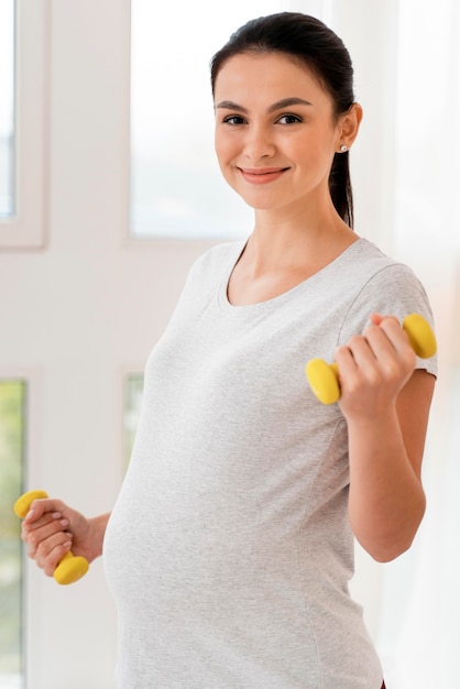 Front view pregnant woman training with weights