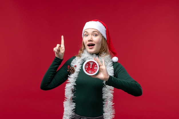 Free photo front view pretty female holding clock on a red background