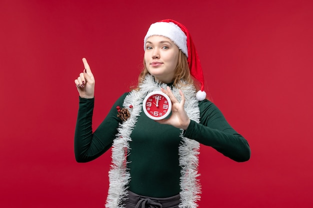 Free photo front view pretty female holding clock on red background