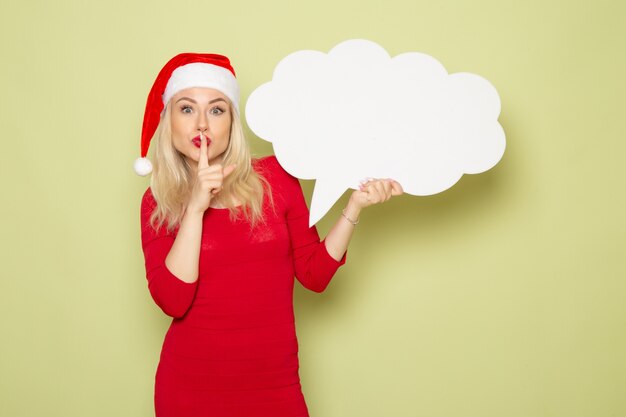 Front view pretty female holding cloud shaped white sign on green wall christmas snow photo holidays emotion new year