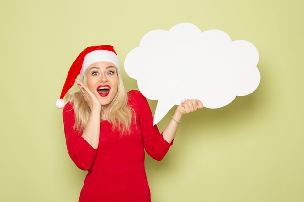 Front view pretty female holding cloud shaped white sign on green wall emotion snow new year holiday christmas