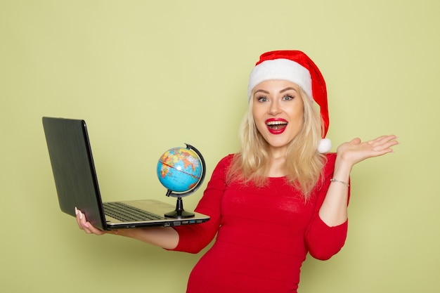 Free Photo front view pretty female holding little earth globe and laptop on green wall christmas color snow holidays new year emotion