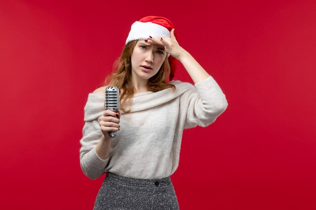 Front view of pretty female holding mic on red