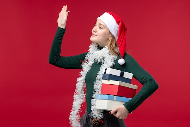 Free photo front view pretty female holding new year presents on a red background