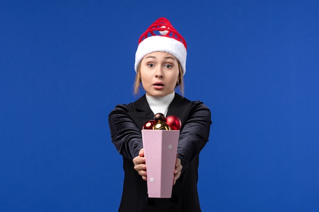 Free photo front view pretty female holding plastic tree toys on blue wall blue holiday new year