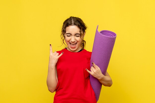 Front view of pretty female holding purple carpet on yellow