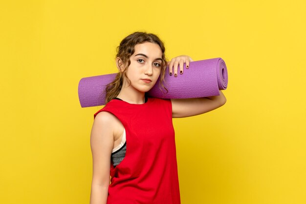 Front view of pretty female holding purple carpet on yellow