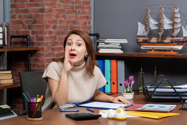 Front view of pretty woman saying something working in office