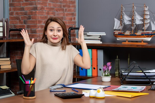 Front view of pretty woman showing her surprise working in office