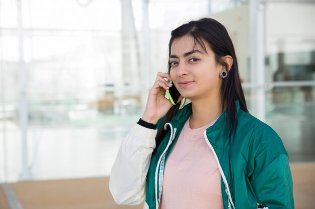 Front view of pretty woman talking on phone, looking at camera