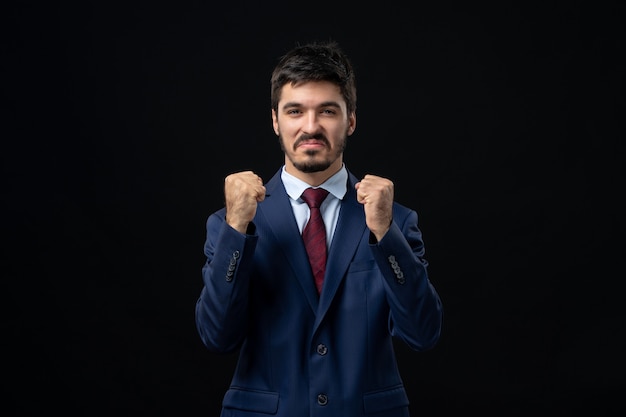 Free photo front view of proud and emotional young man enjoying his succeess on isolated dark wall