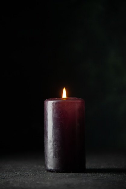 Front view of purple candle on dark