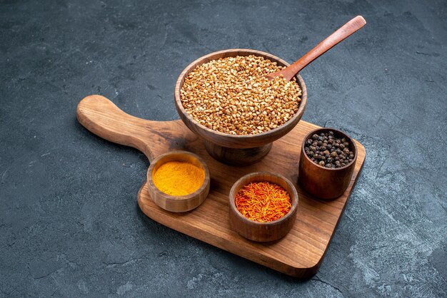 Front view raw buckwheat with seasonings on dark-grey space