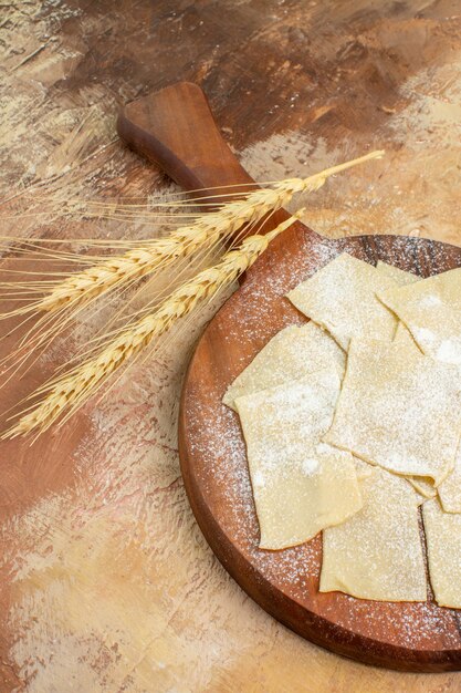 Front view raw dough slices with flour on a cream desk pasta dish cuisine