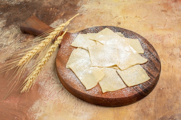 Front view raw dough slices with flour on cream desk