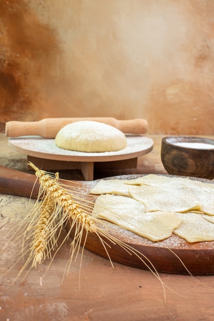 Front view raw dough slices with flour and seasonings on cream desk