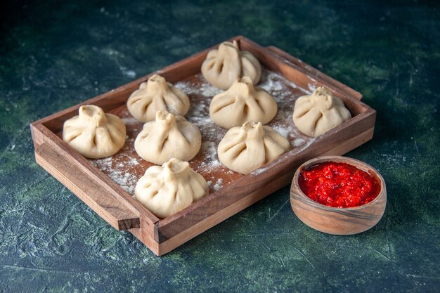 Front view raw dumplings with meat inside on dark surface dish color meal flour cooking pepper dough meat