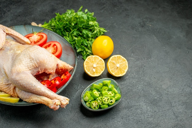 Front view raw fresh chicken inside plate with greens lemon and vegetables on dark background food color meat  chicken animal